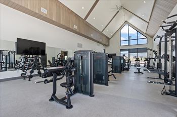 Spacious gym with a variety of equipment and a flat screen tv mounted on the wall